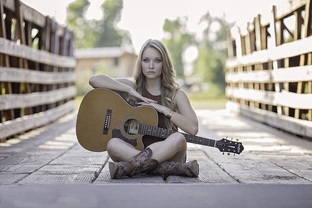 female guitarist sits on bridge