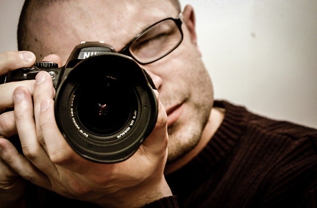 Photographer using DSLR with petal lens hood