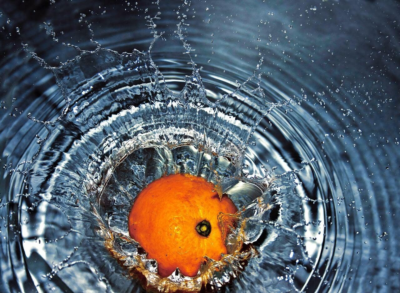 High speed photo of orange splashing into water