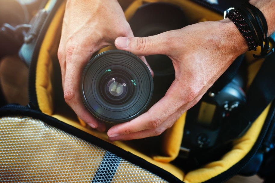 photographer properly packing camera lens in bag