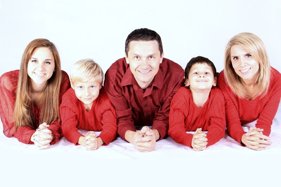 A family with mother, father, two boys and a girl wearing matching red tops.