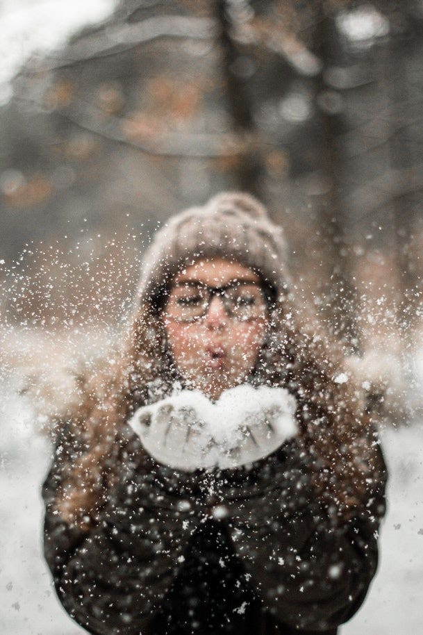 Girl blowing powdered snow from hands