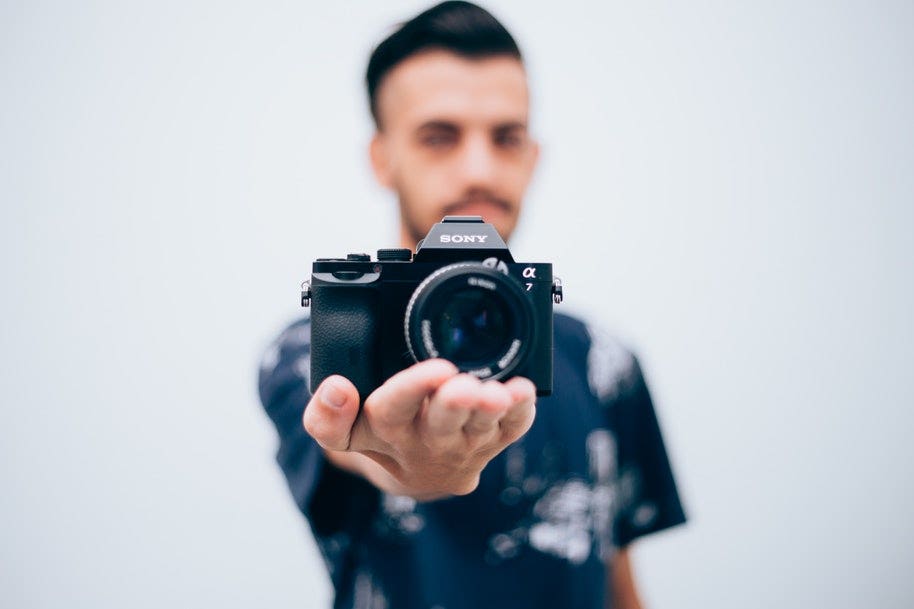 man holding sony mirrorless camera