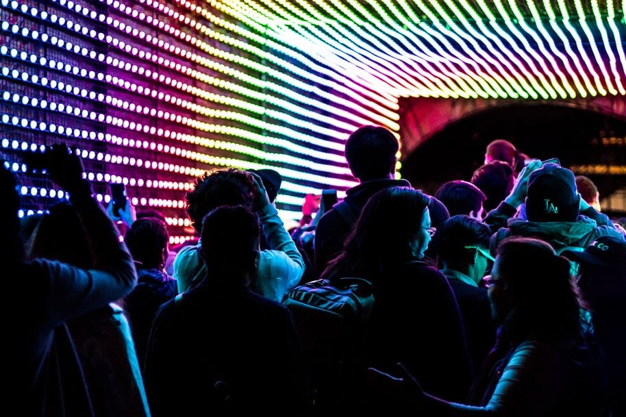 people walking through light tunnel