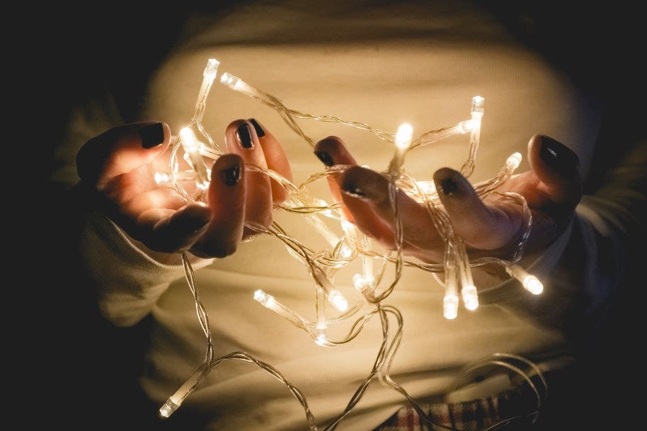 Two hands holding strings of fairy lights.