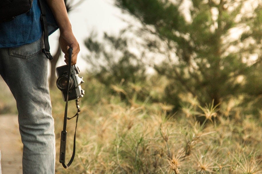 photographer holding camera with camera strap