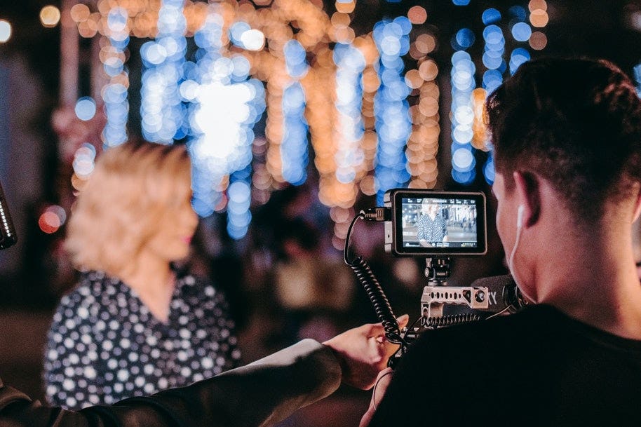 man shooting video of woman