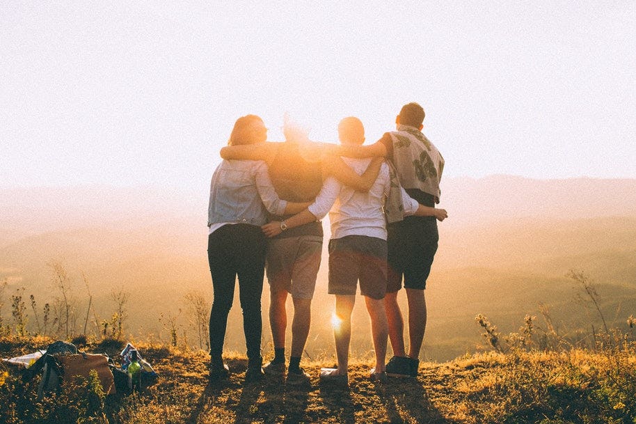 group of friends on hilltop watching sunrise
