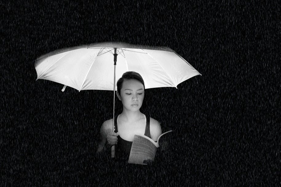 woman holding umbrella while reading book