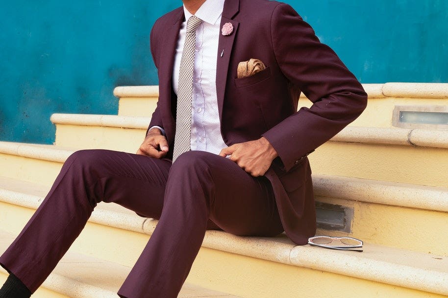 A man wearing formal suit and sitting on stairs.