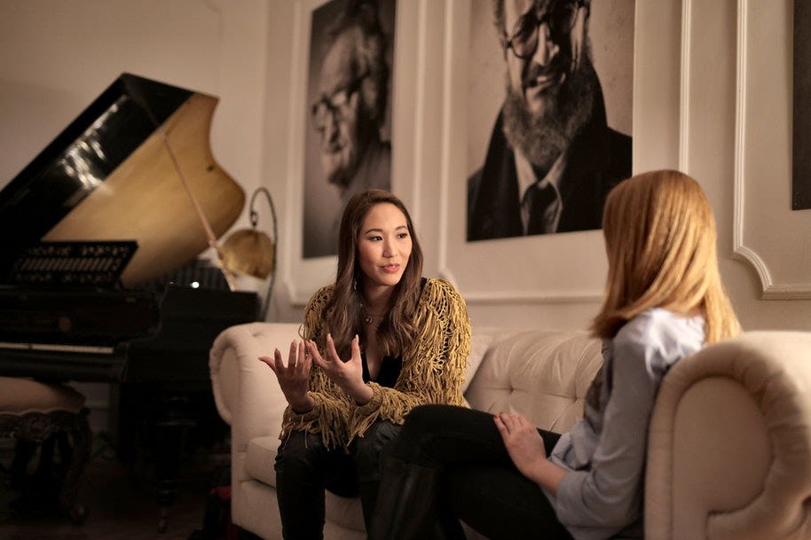 two women talking on a couch in a video interview.