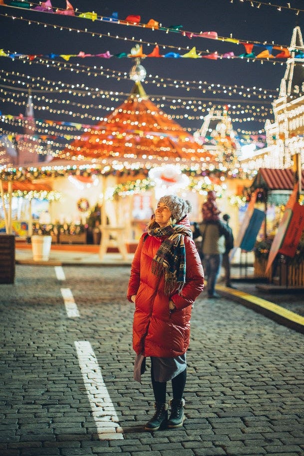 Woman looking at Christmas lights in street.