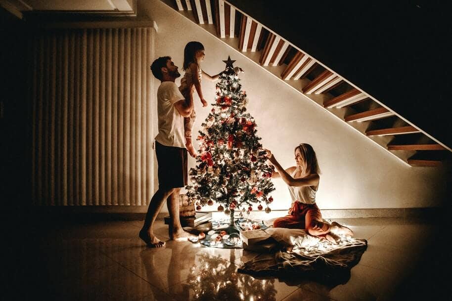 A father holding up his daughter to put the star on the Christmas tree