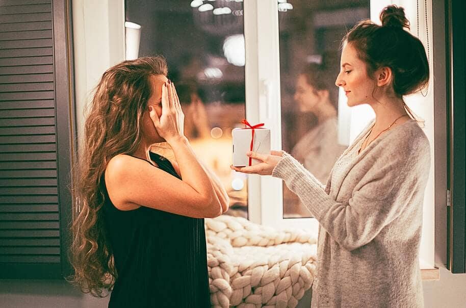 Two girlfriends giving each other Christmas gifts