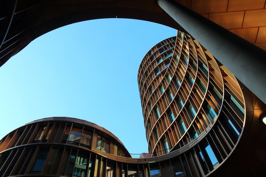 A view from below of a curvy wooden building..